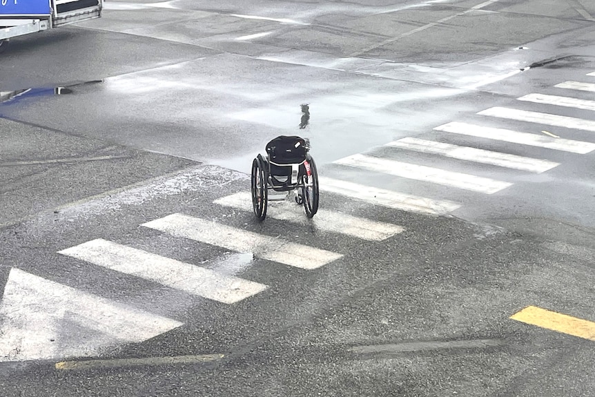 A wheelchair alone on a crosswalk on the airport tarmac